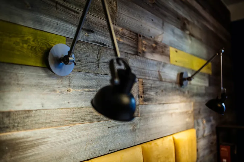 Szare deski ścienne ze starego drewna w restauracji z industrialnymi lampami
