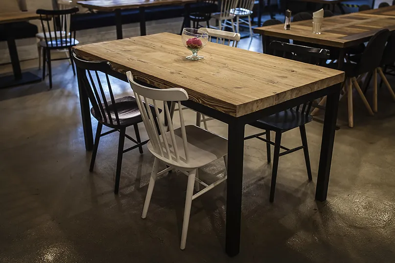 Stół ze starego drewna i metalu ORLANDO w restauracji — smukła czarna podstawa