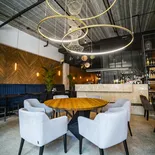 Stół DALLAS w kawiarni pod okrągłymi lampami — blat ze starego drewna i sześć foteli