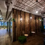 Lounge z drewnianą ścianą z ciemnobrązowych desek ze starego drewna i roślinami