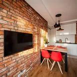 Stare cegły na ścianę w otwartym salonie z białą kuchnią – aranżacja loft